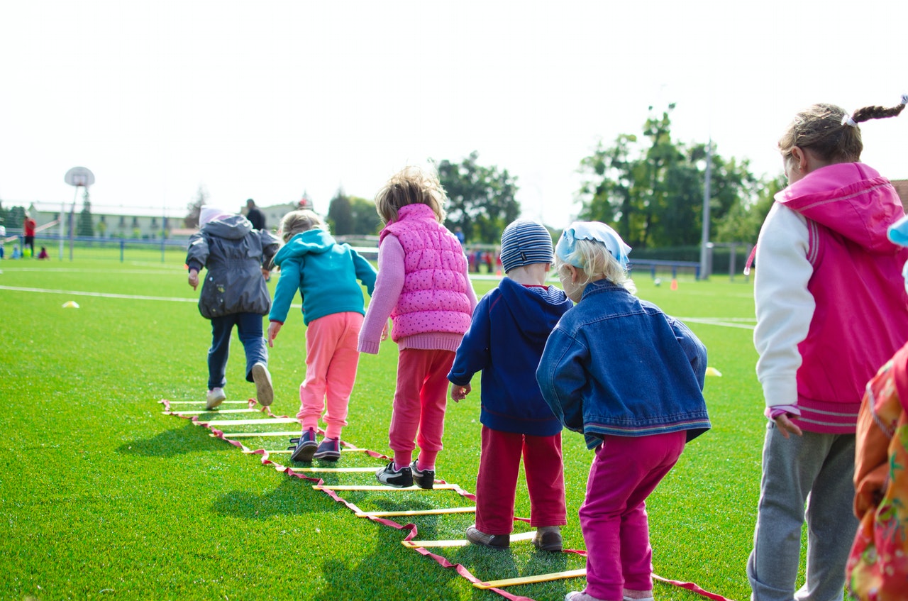 Children hop through ladder on ground at summer camp